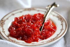 a white plate topped with red sauce and a silver fork on top of a table