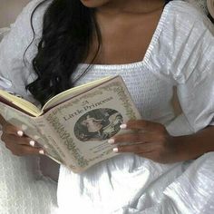 a woman is reading a book in bed