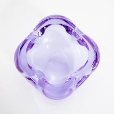 a purple glass vase sitting on top of a white table