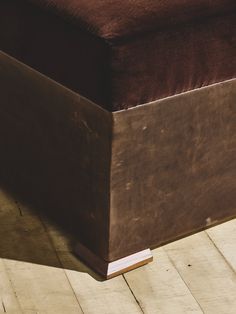 a brown ottoman sitting on top of a wooden floor