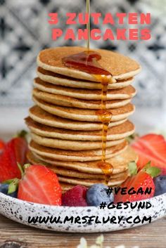 pancakes stacked on top of each other with syrup being drizzled over them