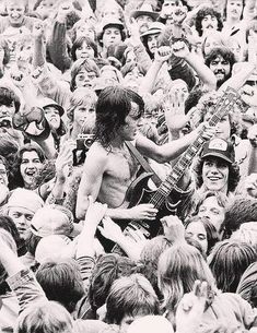 a large group of people are in the middle of a concert and one person is holding an electric guitar