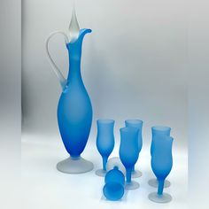 a blue glass pitcher and five glasses