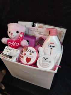 a pink teddy bear sitting in a white box filled with personal care products and toiletries