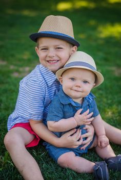 two young boys are sitting on the grass