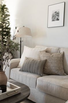 a living room with a couch, coffee table and christmas tree in front of it