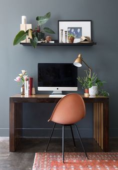 a woman sitting at a desk in front of a computer on top of a wooden table