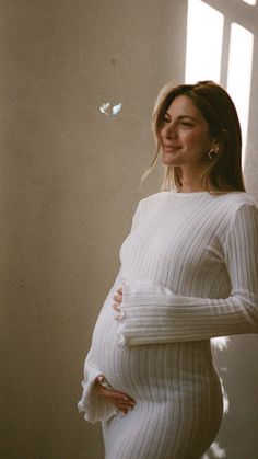 a pregnant woman standing in front of a window