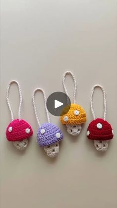 four crocheted mushrooms are hanging from strings on the wall, and one is wearing a