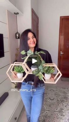 a woman standing in a living room holding up two planters that are shaped like hexagons