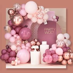 a party decoration with balloons, candles and other items on a shelf in front of a pink backdrop