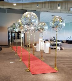 balloons are lined up on the red carpet in front of an empty room with tables and chairs