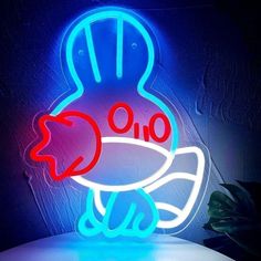 a blue and red neon sign with a fish in it's mouth on a table