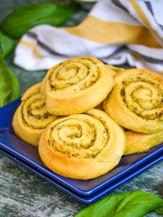 three cinnamon rolls on a blue plate with green leaves