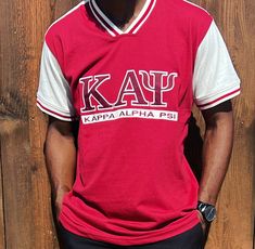 Show off your loyalty and pride for Kappa Alpha Psi fraternity with this stylish shirt. Made with high-quality materials, this shirt is perfect for any member  of the organization. The design prominently displays the fraternity's letters, ensuring that you will stand out and make a statement wherever you go. Whether you're attending a fraternity event or just want to show off your Greek pride, this Kappa Alpha Psi shirt is the perfect addition to your wardrobe. Fast Shipping & Processing: 1-2 da Short Sleeve Tops With Embroidered Graphics For College, Team-colored Cotton Tops With Embroidered Graphics, Red Collegiate Tops With Embroidered Logo, Varsity Style Top With Embroidered Graphics For Fan Gear, Casual Tops With Embroidered Logo For Fan Gear, Cotton Tops With Embroidered Graphics For Fan Gear, Fitted School Spirit T-shirt For College, Fitted College T-shirt With School Spirit, Red Embroidered Logo Top For College