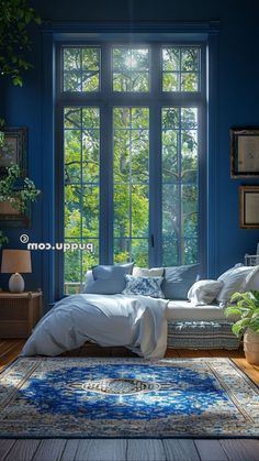 a living room with blue walls and large windows that look out onto the trees outside