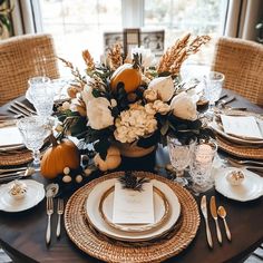 a dining table set for thanksgiving dinner with pumpkins and flowers in the centerpiece