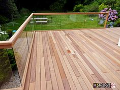 a wooden deck with glass railing and bench