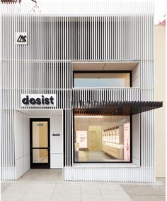 a white building with black and white stripes on the front, and an open door that says dosist