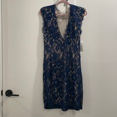 a blue lace dress hanging on a white door with a hanger in front of it