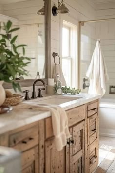 a bathroom with two sinks and a bathtub in the middle, surrounded by greenery