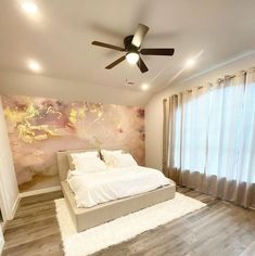 a bedroom with a bed, ceiling fan and large window curtained area in front of it