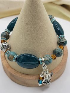 This blue jade just does not photograph well - it is a beautiful shade of teal blue paired here with amber crystal , Emperor Jasper and TIbetan silver.  The look is completed with Silver Prayer bead and dangling feminine charms. Jade is the symbol of serenity, purity, harmony and health. Companion pieces, stackables and custom available by contacting Teresa:) Blue Bracelets With Natural Stones And Czech Glass, Handmade Blue Jade Beaded Bracelets, Blue Jade Bracelets For Healing, Handmade Blue Jade Beaded Bracelet, Blue Beaded Jade Bracelets, Blue Czech Glass Bracelets With Natural Stones, Blue Jade Bracelet, Blue Jade Jewelry For Meditation, Blue Jade Spiritual Bracelets