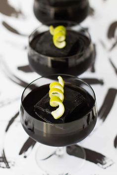 three desserts in small black bowls on a table