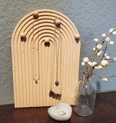 a vase filled with white flowers next to a wooden wall hanging on it's side