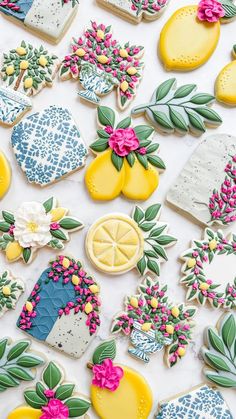 some decorated cookies are laying on a white tablecloth with pink flowers and lemons