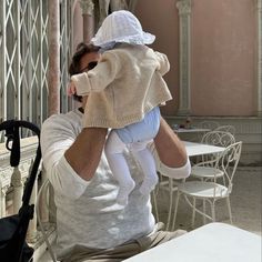 a man holding a child in his arms while sitting at a table with chairs and tables