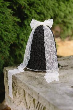 a black and white hat sitting on top of a stone wall next to some trees