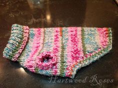 a pink, blue and green striped knitted mitt on a black counter top