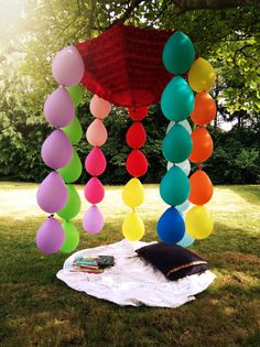 a bunch of balloons that are hanging from a canopy in the grass with some books on it