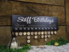 a sign that says staff birthdays hanging from the side of a wooden wall with earrings on it