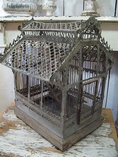 an old birdcage sitting on top of a wooden table