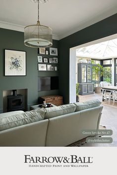 a living room with green walls and pictures on the wall above it's fireplace