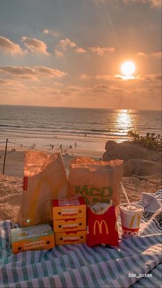 the sun is setting at the beach with mcdonald's bags and snacks on it