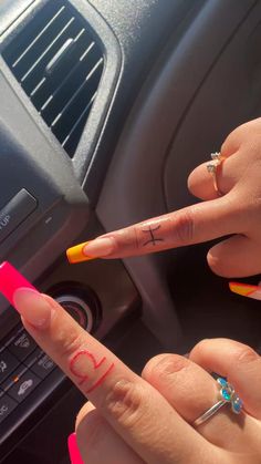 two people with tattoos on their fingers are sitting in a car and pointing to the left