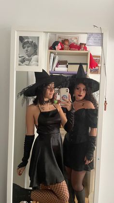 two women dressed up as witches in front of a mirror