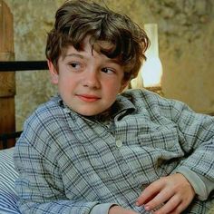 a young boy sitting on top of a bed