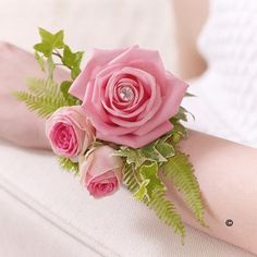 a pink rose and green fern corsage on a woman's arm,