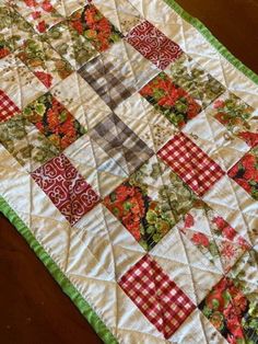 a quilted table runner with red and green flowers on it