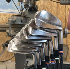 a bunch of golf clubs are stacked on top of each other in front of a machine