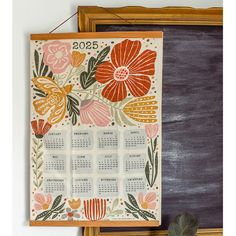 a calendar hanging on the wall next to a chalkboard with flowers painted on it