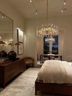 a bedroom with a chandelier hanging from the ceiling next to a large bed