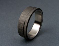 a wedding ring made from wood and stainless steel on a blue surface with a black center