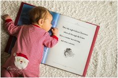 a baby laying on the floor reading a book