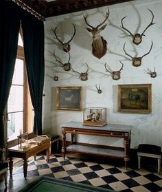 there are deer heads mounted on the wall in this room with checkered flooring