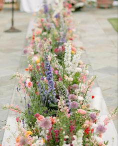 a long row of flowers sitting next to each other on top of a stone floor